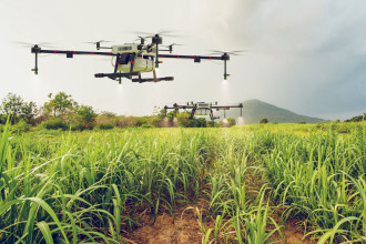 Image of drones flying over a field and fertilizing crops