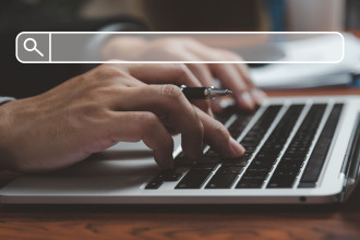 Image of a person typing on a keyoard while holding a pen