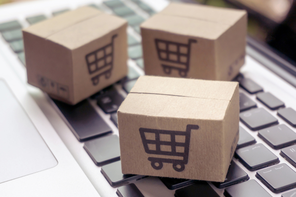 Image of Three Packages with a Shopping Cart Symbold on them Laying on a Keyboard of a Gray Laptop