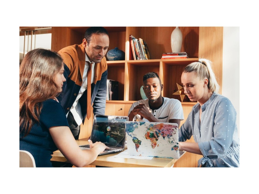 Image of a group of people who work at their laptops, while one of the laptops has a world map on them.