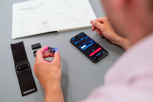 Image of a person holding up a device with LED lights in their hands and a phone and notebook infront of them.