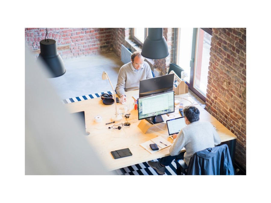 Image of two people woring at their computers in a brick walled office