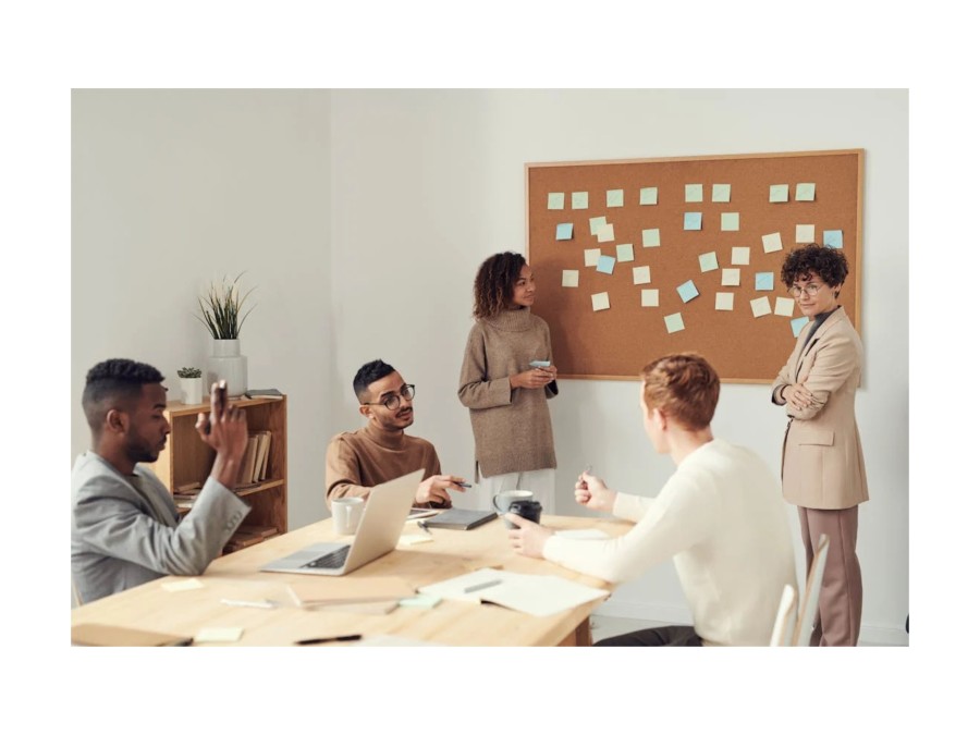 Image of a group of people that is brainstorming ideas, while they put note on a pin board