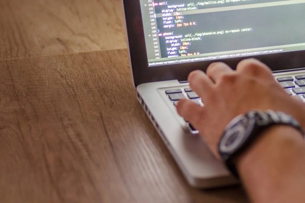 Image of a Person's Arm with a Watch and a Laptop with Code on it