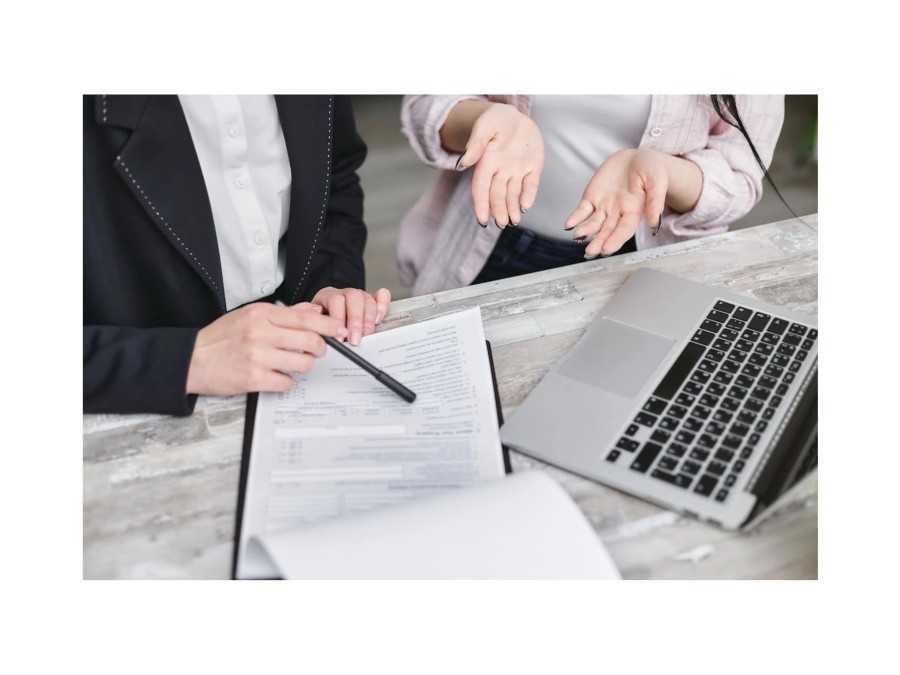 Image of Two People Looking at a Document and Talking about it, while one 