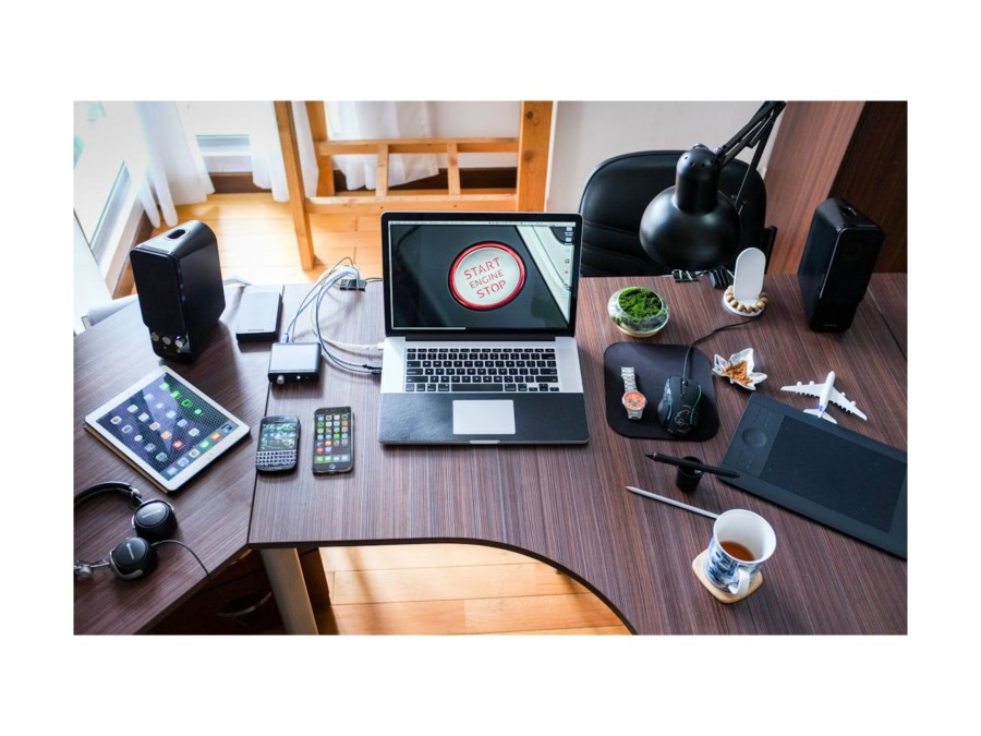 A table with a lot of electronic devices, mainly consumer electronics, on it.