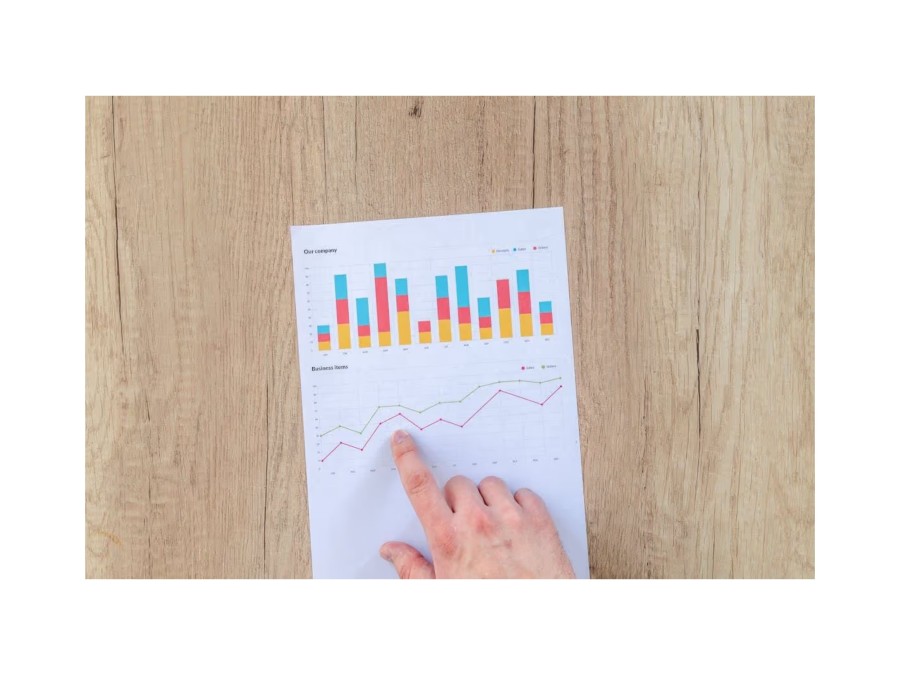 Image of a Person Pointing on a Graph on a Piece of Paper with its Finer