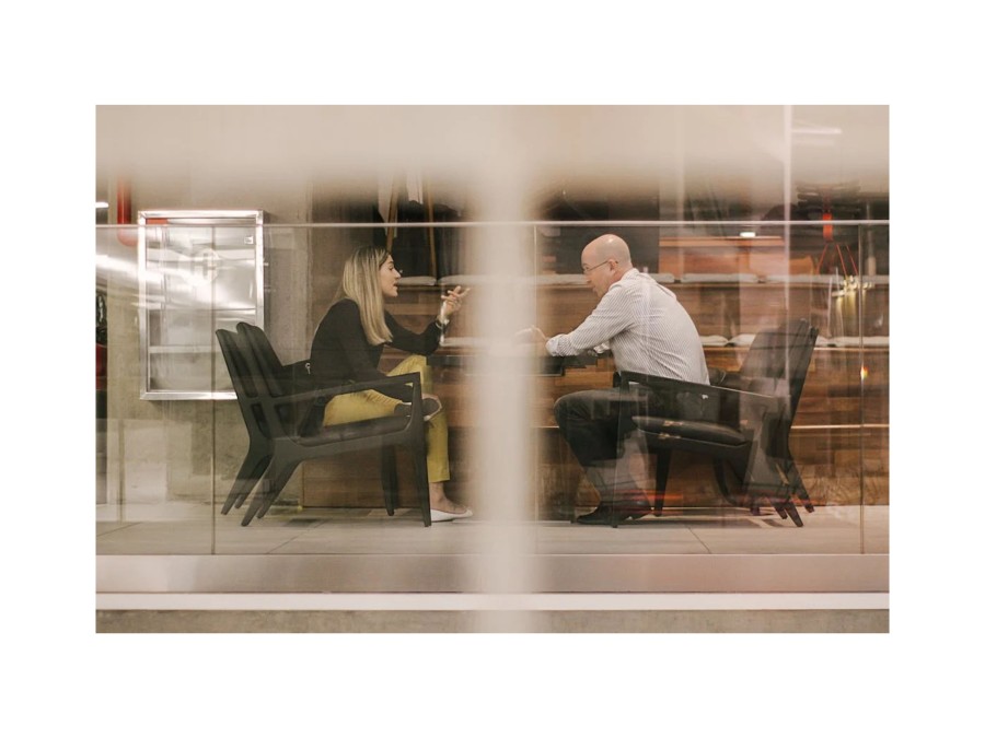 Image of a Man and a Woman Sitting on Black Chairs and Talking